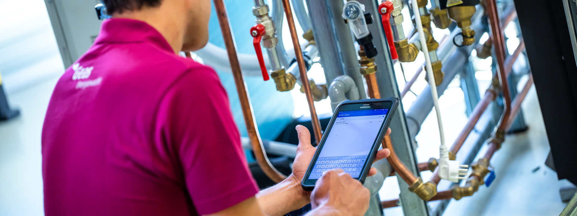 Monteur voert gegevens in op tablet tijdens inspectie van leidingen.