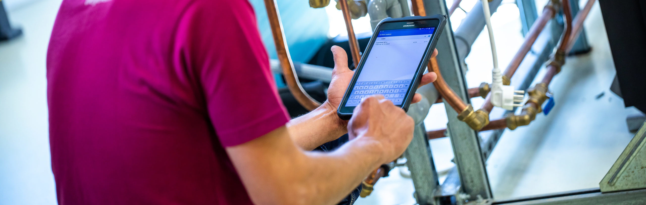 Monteur voert gegevens in op tablet tijdens inspectie van leidingen.